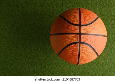 Close-up. Basketball Ball On A Green Basketball Court. There Are No People In The Photo. Minimalism. Professional And Amateur Sports, Outdoor Activities, Training, Advertising.