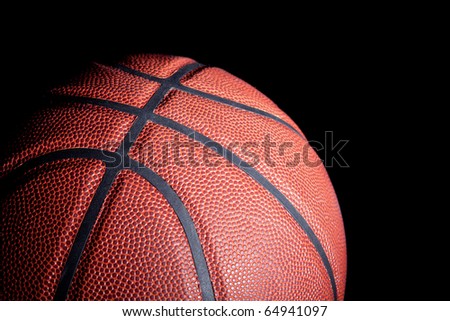 Close-up of a basketball with dramatic side lighting on a black background.