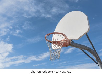 Close-up a basketball hoop in public arena at community park in Irving, Texas, USA. Side view of rim and white backboard under cloud blue sky