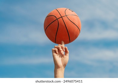 Close-up of a basketball player spinning a ball on his finger under a clear blue sky.

 - Powered by Shutterstock