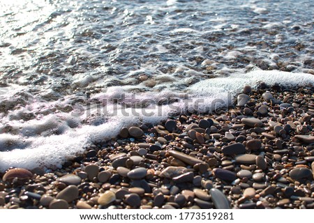 close-up of a beach wave on shiny stones. Background. Textures