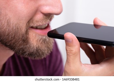 Close-up Of A Beard Man Using Voice Recognition Function On Mobile Phone Against White Background
