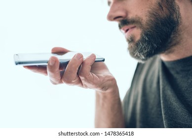 close-up of bearded caucasian man recording voice message or using voice assistant on mobile phone - Powered by Shutterstock