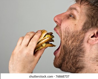 Close-up of bearded man eating juicy hamburger