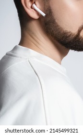 Closeup of bearded man's ear iwith white wireless earbuds