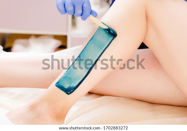 Close-up Of A Beautician Depilation With Hot\
Wax Woman\'s Leg In Beauty Spa. Body hair removal. Hair removal\
process on female leg with\
epilation
