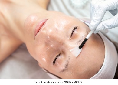Close-up beautician doctor hand making anti-age procedure apply peeling acid young attractive female client at beauty clinic. Cosmetologist specialist doing skincare treatment. Health care therapy