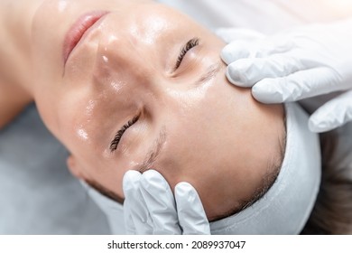 Close-up beautician doctor hand making anti-age procedure massage peeling for young attractive female client at beauty clinic. Cosmetologist specialist doing skincare treatment. Health care therapy