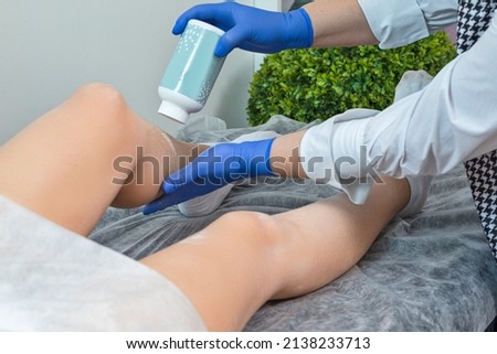 Closeup of beautician hands doing depilation to beautiful woman legs with wax and powder in a beauty salon.Horizontal image
