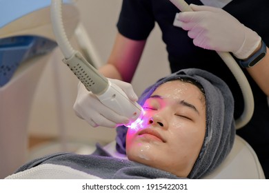 Closeup Of Beautician Using Laser Therapy For Facial Skin Rejuvenation. Beautiful Healthy Woman Face Getting Skin Resurfacing In Spa Salon.