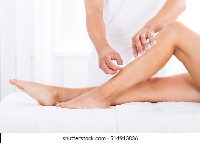 Close-up Of A Beautician Waxing Woman's Leg In Beauty Spa