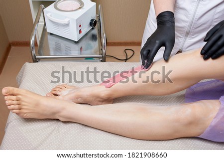 Closeup Of Beautician Waxing Woman's Leg In Beauty Spa