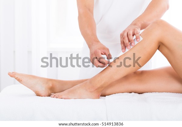 Close-up\
Of A Beautician Waxing Woman\'s Leg In Beauty\
Spa