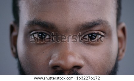 Close-up of beautiful black man eyes staring at camera. Portrait detail of serious confident african american man.
