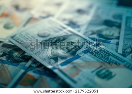Close-up beautiful clean new one hundred dollar bill lies on other one hundred dollar bills in blue tones