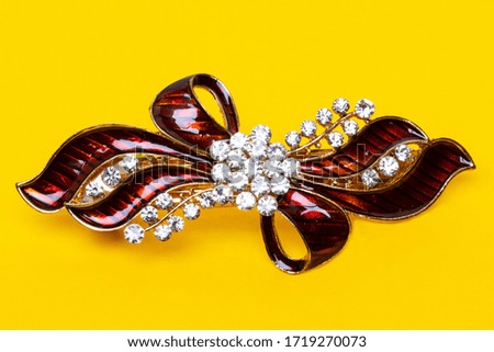 Close-up of a beautiful elegant luxurious hair clip or hair pin with rhinestones on a yellow background. Macro photograph.