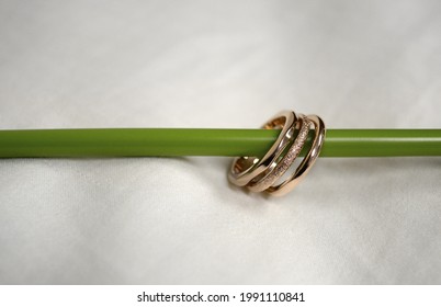 A Closeup Of The Beautiful Golden Precious Rings On The Green Pedicel