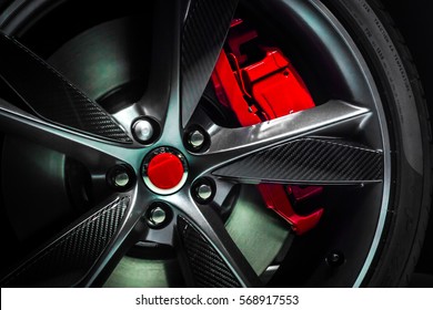 Closeup of beautiful Large Alloy wheel of expensive supercar having painted break callipers and large disc brake 
