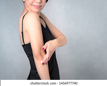 Closeup Of A Beautiful Middle Aged Woman In Black Inner Wear Applying Daily Skincare On Her Elbow - Rough And Dry, Lack Elasticity, Aging Skin Problem, Dermatology, Beauty, Body And Skincare Concept.