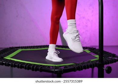 Close-up of beautiful muscular female legs in white sneakers on mobile mini trampoline. Energetic young fitness girl in red tracksuit. Jumping workout. High intensity interval cardio training - Powered by Shutterstock