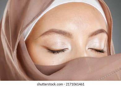 Closeup Of A Beautiful Muslim Woman Covering Her Beauty With Her Scarf And Showing Shimmery Eyeshadow. Face Of A Stunning Muslimah Closing Her Eyes And Showing Perfect Eye Makeup Look With A Hijab