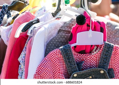 Close-up Of Beautiful Second Hand Baby Girl And Child Clothes Displayed At Outdoor Garage Sale For Shopping, Reusing, Exchanging, Recycling Or Donating