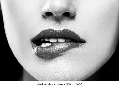 Closeup of beautiful sexy plump woman lips with lipstick biting black and white