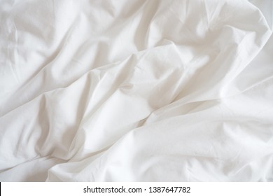 Closeup of beautiful white shiny crumpled polyester fabric sheets on the bed with warm motion and feeling for background and decoration Cloth washing and laundry concept at home - Shutterstock ID 1387647782