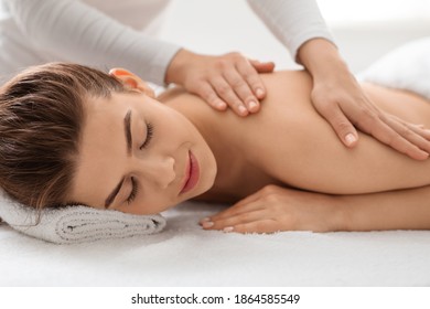 Closeup of beautiful woman enjoying back massage at luxury newest spa. Peaceful young lady with closed eyes laying on massage table, having body healing session at romantic atmosphere - Powered by Shutterstock