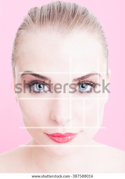 Close-up of beautiful woman face with makeup\
and divided lines as anti-aging and face lifting concept against\
pink or purple\
background