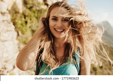 Close-up Of A Beautiful Woman On Mountain Trail With Her Hair Flying. Female Mountaineer With Hair Flying In Wind.