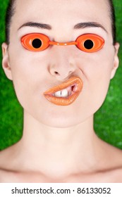 Closeup Of A Beautiful Woman Wearing Tanning Bed Glasses And Pulling A Strange Face Isolated On Green