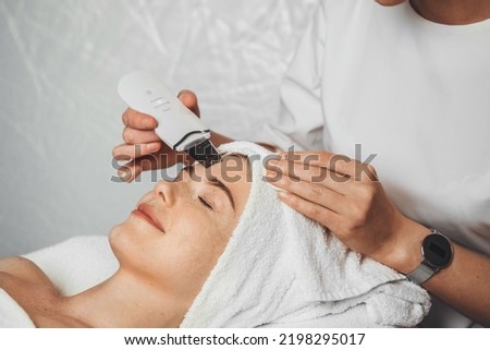 Close-up of beautiful woman's face during ultrasonic peel skin procedure at spa salon. Ultrasound facial peeling. Ultrasonic facial cleansing at cosmetology