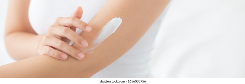 Closeup beautiful young asian woman smile applying sunscreen cream lotion on skin care at bedroom, beauty asia girl makeup and cosmetic for smooth, wellness and health concept, banner website.