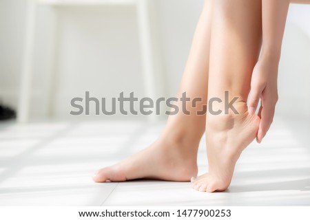 Closeup beautiful young asian woman applying cream and lotion onto foot dry on bed, beauty asia girl moisturizer and treatment cosmetic onto toes and heel, skincare cosmetic and healthy concept.