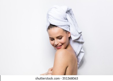 close-up of beautiful young woman with bath towel on head covering her breasts, on white