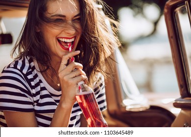 Closeup Of Beautiful Young Woman Enjoying Drinking Cola With Straw While Sitting In A Car. Female On A Road Trip Having Soft Drink.