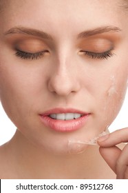 Close-up Of Beautiful Young Woman Removing Old Damaged Skin From Her Face