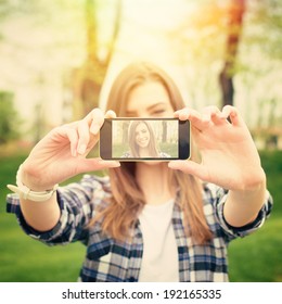 Closeup Of Beautiful Young Woman Taking A Selfie Photo With Smart Phone Outdoors On Sunny Summer Day. Instant Filter. Square Image.