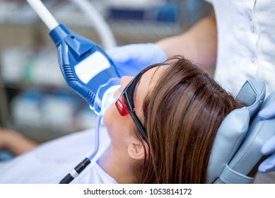 Close-up Of Beautiful Young Woman In Visit At The Dentist Office, Whitening Teeth With Ultraviolet Light.