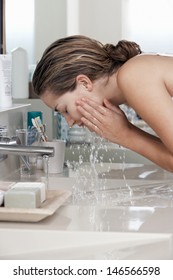 Closeup of beautiful young woman washing face in bathroom