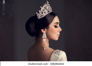 Closeup beauty portrait of young beautiful bride with hairstyle, diamond crown and earring. Brunette woman