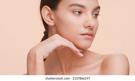 Close-up beauty portrait of young woman who gently strokes her pure skin with her hand from the jawline to the neck and shoulder | Body care and healthy skin.
