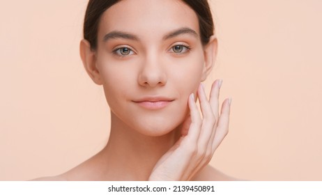 Close-up beauty portrait of young woman who softly touches her chin with back of her hand and gently lay fingers on the jowl or chin | Pure skin and skin care concept.