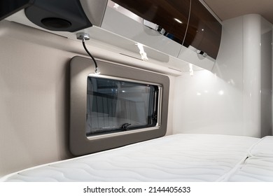 Closeup Of Bed Near Window And Storage Shelves Inside Empty Bedroom In Luxury RV Camper Trailer Interior