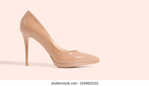 Closeup beige women patent leather shoe isolated on pink background. Stilettos shoe type. Summer fashion and shopping concept. Luxury, glamour party ladies wardrobe accessory. Selective focus. Banner - Powered by Shutterstock