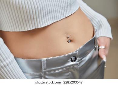 Closeup of a belly button naval that is pierced with jewelry
