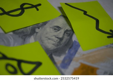 A close-up of Benjamin Franklin on a U.S. dollar bill, partially covered by bright sticky notes featuring dollar symbols and a downward arrow, symbolizing financial trends and economic changes. - Powered by Shutterstock