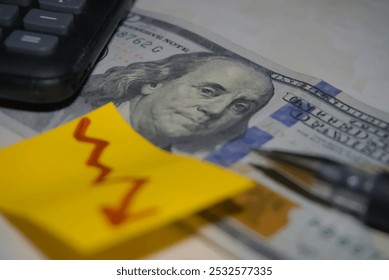 A close-up of Benjamin Franklin on a U.S. dollar bill, partially covered by bright sticky notes featuring dollar symbols and a downward arrow, symbolizing financial trends and economic changes. - Powered by Shutterstock