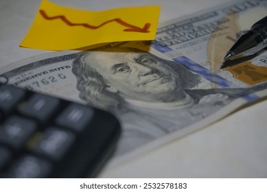 A close-up of Benjamin Franklin on a U.S. dollar bill, partially covered by bright sticky notes featuring dollar symbols and a downward arrow, symbolizing financial trends and economic changes. - Powered by Shutterstock